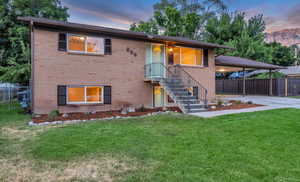 View of front of home featuring concrete driveway, brick siding, an attached carport, and stairs