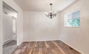 Empty room featuring a chandelier and wood finished floors
