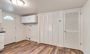 Washroom featuring cabinet space, wood finished floors, hookup for an electric dryer, a textured ceiling, and hookup for a washing machine