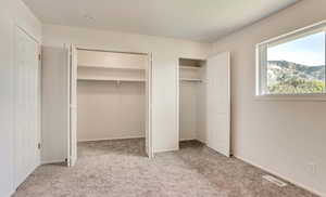 Unfurnished bedroom with carpet floors and two closets
