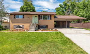 View of front of house with brick siding, driveway, and a carport