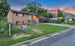 View of front of property with driveway, brick siding, a mountain view, and a carport