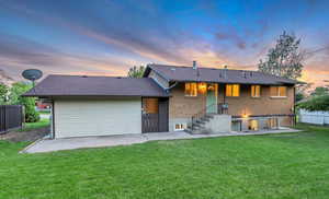 Back of house at dusk with brick siding, a patio, and a shingled roof