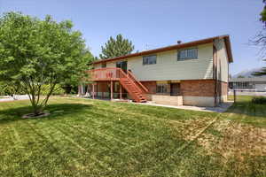 Rear view of house featuring stairs, a deck, and brick siding