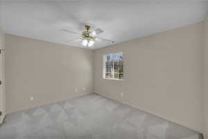 Unfurnished room with ceiling fan, light carpet, and a textured ceiling