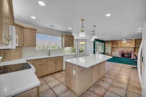 Kitchen with white appliances, light countertops, ceiling fan, an island with sink, and recessed lighting