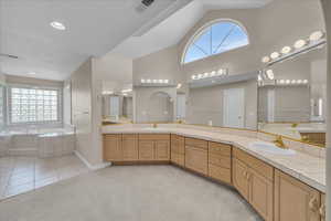 Full bath featuring double vanity, a garden tub, and high vaulted ceiling