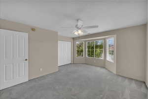 Unfurnished bedroom featuring carpet flooring, a closet, a ceiling fan, and a textured ceiling