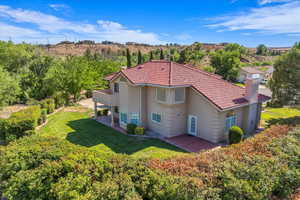 Back of property with a patio area, a lawn, stucco siding, and a chimney