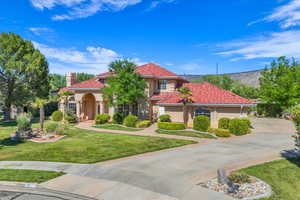 Mediterranean / spanish-style house with stucco siding, a tiled roof, a front lawn, and a chimney