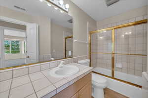 Full bathroom with vanity, wood finished floors, and enclosed tub / shower combo