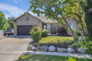 View of front of property with a garage, stucco siding, driveway, and brick siding