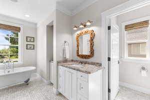Bathroom with vanity, a soaking tub, crown molding, and recessed lighting