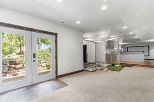 Unfurnished living room with carpet, recessed lighting, and french doors