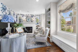 Living area featuring dark wood-type flooring, a brick fireplace, and recessed lighting