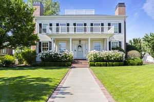 View of front of house featuring a balcony, a chimney, and a front yard