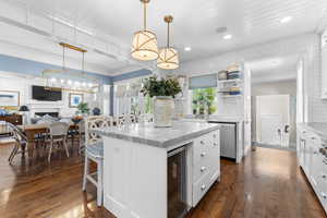 Kitchen featuring wine cooler, a center island, white cabinetry, a breakfast bar, and light stone countertops