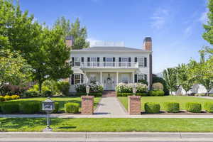 View of front of home with a balcony, a chimney, and a front yard