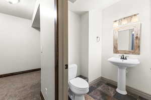 Half bathroom featuring a textured ceiling and stone finish flooring