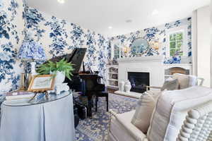 Living room featuring wallpapered walls, wood finished floors, a fireplace, and recessed lighting