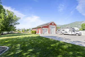 View of green lawn featuring an outbuilding, a mountain view, and a detached garage