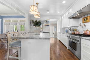 Kitchen featuring high end stove, exhaust hood, healthy amount of natural light, tasteful backsplash, and recessed lighting