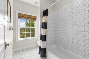Full bath featuring baseboards and shower / bath combo with shower curtain