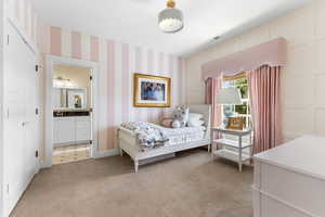 Bedroom featuring light carpet, wallpapered walls, and ensuite bath