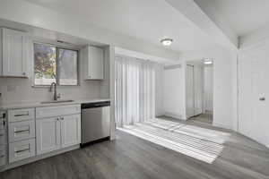 Kitchen featuring dark wood-style flooring, stainless steel dishwasher, and white cabinets
