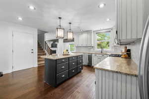 Kitchen featuring dishwasher, a center island, dark wood finished floors, tasteful backsplash, and pendant lighting