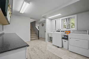 Kitchen featuring washer and dryer, light tile patterned floors, and white cabinetry