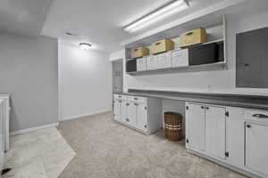 Kitchen with open shelves, electric panel, dark countertops, a textured ceiling, and white cabinets