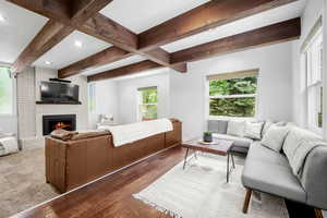 Living area with beam ceiling, recessed lighting, a fireplace, and hardwood / wood-style flooring