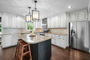 Kitchen featuring stainless steel appliances, dark wood-type flooring, white cabinets, and recessed lighting