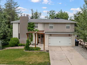 View of front of house featuring brick siding, an attached garage, a front lawn, driveway, and a shingled roof