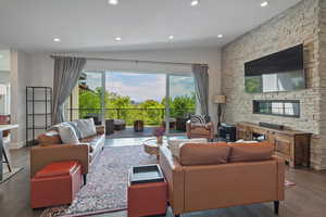 Living room with recessed lighting, wood finished floors, a fireplace, and lofted ceiling