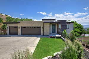 Contemporary house with a garage, concrete driveway, stone siding, a front lawn, and stucco siding