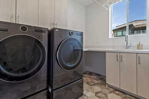Laundry room with cabinet space, separate washer and dryer, and stone finish floors