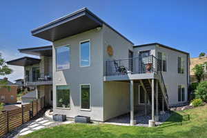 Back of house with stucco siding and stairway