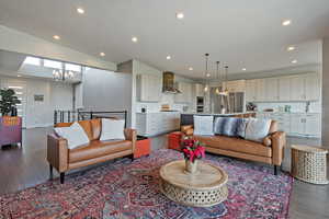 Living area with a chandelier, lofted ceiling, dark wood-style floors, and recessed lighting