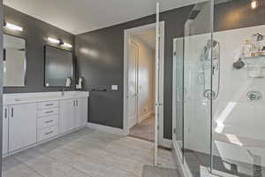 Full bathroom with double vanity and a stall shower