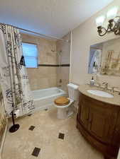 Bathroom featuring vanity, shower / bath combo with shower curtain, a textured ceiling, and a chandelier