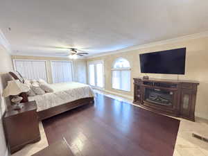 Bedroom featuring multiple closets, crown molding, a textured ceiling, wood finished floors, and ceiling fan