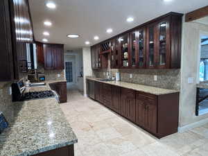 Kitchen featuring dishwashing machine, backsplash, recessed lighting, gas stove, and dark brown cabinets