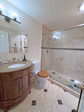 Full bath featuring a textured ceiling, a shower stall, and vanity