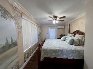 Bedroom with a wall mounted AC, ornamental molding, ceiling fan, and wood finished floors