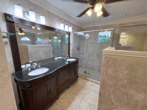 Full bathroom with a ceiling fan, double vanity, a stall shower, tile patterned flooring, and crown molding