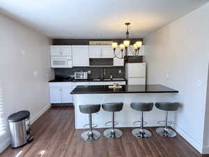 Kitchen featuring white appliances, a chandelier, dark countertops, and decorative backsplash