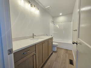 Bathroom with vanity, wood finished floors, shower / washtub combination, and recessed lighting