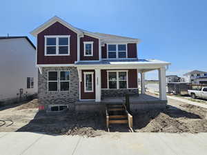 View of front of house featuring covered porch, board and batten siding, and a metal roof